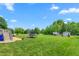 Spacious backyard with green grass, trees, a trampoline, RV, and a shed under a clear blue sky at 724 Harolds Northfield Dr, Cedar Grove, NC 27231