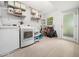 Modern laundry room featuring tile flooring, utility sink, washer, dryer and shelving at 7605 Copper Mine Ln, Raleigh, NC 27615