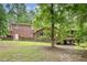 Expansive backyard featuring a brick home with deck, complemented by lush greenery and mature trees at 7801 Wood Way Ct, Raleigh, NC 27606