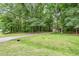 Scenic property view with a long driveway leading to a brick home surrounded by lush greenery at 7801 Wood Way Ct, Raleigh, NC 27606