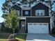Charming two-story home with a modern dark exterior, a two-car garage, and a well-maintained front yard at 809 Trinity Park Dr, Wake Forest, NC 27587