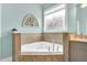 Corner bathtub with tile surround and a unique corner window in a bright and airy bathroom at 921 Riverwood Dr, Clayton, NC 27527