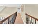 A carpeted hallway with iron railing, neutral walls, and modern lighting fixtures at 921 Riverwood Dr, Clayton, NC 27527