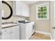 Functional laundry room featuring a sink, white cabinets, and modern washer and dryer at 921 Riverwood Dr, Clayton, NC 27527