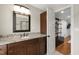 Bathroom vanity with granite counters, dark wood cabinets, updated light fixture, and entry to the Primary closet at 101 Eden Glen Dr, Holly Springs, NC 27540