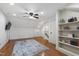 Finished bonus room featuring hardwood floors, a ceiling fan, and custom built-in bookshelves at 101 Eden Glen Dr, Holly Springs, NC 27540