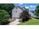 Back of home featuring an attached garage and well-manicured lawn with lush trees and landscaping at 101 Eden Glen Dr, Holly Springs, NC 27540