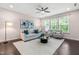 Comfortable living room with neutral tones, plush seating, ceiling fan, large windows, and hardwood flooring at 1049 Lakebrink Dr, Morrisville, NC 27560