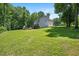 Spacious backyard with lush lawn leading to the home's deck and a stone patio with an outdoor fireplace at 110 Lexington Ave, Zebulon, NC 27597