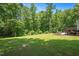 Large, grassy backyard offering a tranquil setting with a wooded perimeter, deck, and patio visible at 110 Lexington Ave, Zebulon, NC 27597