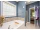 Bathroom featuring a tub with tile surround and mosaic accents, with a window providing natural light at 110 Lexington Ave, Zebulon, NC 27597