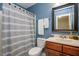 Bathroom showcasing a striped shower curtain, a dark vanity with a white sink, and a large mirror at 110 Lexington Ave, Zebulon, NC 27597