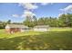 A large backyard features the main house, connecting sunroom, detached garage, and lush green lawn at 1105 Horseshoe Rd, Durham, NC 27703