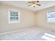 An airy bedroom with two windows, neutral paint, a ceiling fan, and carpet flooring at 1105 Horseshoe Rd, Durham, NC 27703
