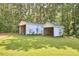 Image shows outbuildings on a well-maintained lawn bordered by lush trees, ideal for storage or hobbies at 1105 Horseshoe Rd, Durham, NC 27703