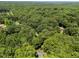 Drone shot displays house nestled among trees in a verdant landscape, blending seclusion with natural beauty at 11425 Horsemans Trl, Raleigh, NC 27613