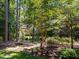 Lush backyard featuring mature trees, mulched garden beds, and a glimpse of the home's exterior at 11425 Horsemans Trl, Raleigh, NC 27613