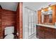Bathroom with wood paneling, glass enclosed shower, vanity, and toilet, offering classic design at 11425 Horsemans Trl, Raleigh, NC 27613