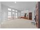 Bright living room featuring carpet flooring, a stone fireplace, and large windows that fill the space with natural light at 11425 Horsemans Trl, Raleigh, NC 27613