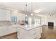 Open-concept kitchen with marble island, stainless steel appliances, white cabinetry, and a view of the fireplace at 123 Gunderson Ln, Garner, NC 27529