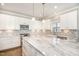 Stylish kitchen featuring white cabinets, marble countertops, stainless steel appliances, and pendant lighting at 123 Gunderson Ln, Garner, NC 27529