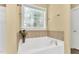 Bathroom featuring a luxurious soaking tub beneath a decorative window, offering a tranquil bathing experience at 123 Holiday Island Dr, Garner, NC 27529