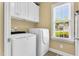 Functional laundry room with modern washer and dryer, storage cabinets and a window at 123 Holiday Island Dr, Garner, NC 27529