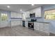 Modern kitchen featuring white cabinets, stainless steel appliances, and plenty of natural light streaming through the windows at 1302 Buffaloe Rd, Garner, NC 27529