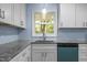 Bright kitchen with white cabinets, granite countertops, and a view of the lush greenery outside the window at 1302 Buffaloe Rd, Garner, NC 27529