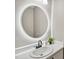 Bathroom with a single sink vanity, round mirror with lights and modern black fixtures at 131 Cricketgrass Dr, Cary, NC 27513