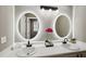 Bathroom with a double sink vanity, large oval mirrors with lights and modern fixtures at 131 Cricketgrass Dr, Cary, NC 27513