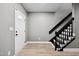 Entryway featuring a staircase with black railings and white trim, complemented by modern flooring at 131 Cricketgrass Dr, Cary, NC 27513