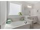 Bright bathroom featuring a soaking tub, window, and neutral tiling at 131 English Violet Ln, Raleigh, NC 27610