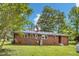 Expansive brick home featuring a chimney and a well-maintained lawn with mature trees and lush landscaping at 1592 Boone Rd, Elon, NC 27244