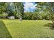 Lush backyard featuring a white outbuilding, a propane tank, and surrounded by mature trees and greenery at 1592 Boone Rd, Elon, NC 27244