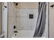 Bathroom featuring white and gray marbled tile, dark fixtures, and a built-in shampoo niche at 1592 Boone Rd, Elon, NC 27244
