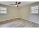 A bedroom featuring wood-look flooring, neutral paint, a ceiling fan, and two windows for natural light at 1592 Boone Rd, Elon, NC 27244