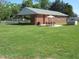 Lush backyard with patio, dining set, and brick home offering a serene outdoor experience at 1700 Warrenton Rd, Henderson, NC 27537