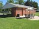 Green backyard with patio, dining set, and brick home, perfect for outdoor entertaining at 1700 Warrenton Rd, Henderson, NC 27537