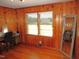 Bedroom featuring wood-paneled walls, natural light, and a classic desk area, blending comfort with character at 1700 Warrenton Rd, Henderson, NC 27537