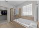 Bright bathroom featuring a walk-in shower, soaking tub, and window at 1711 Happiness Hill Ln, Raleigh, NC 27614