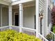 Inviting front porch with classic columns, decorative lighting, and lush landscaping at 1711 Happiness Hill Ln, Raleigh, NC 27614