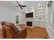 Cozy living room featuring built-in shelving, fireplace, ceiling fan and hardwood floors at 1711 Happiness Hill Ln, Raleigh, NC 27614