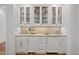 Elegant bar area featuring custom cabinets with glass doors, stone backsplash, and wine refrigerator at 2120 Kipawa St, Raleigh, NC 27607