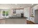 Open kitchen with white cabinets, stainless steel appliances, large windows, and a central island at 2332 Horton Park Dr, Apex, NC 27539