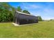 Side view of black metal barn with green lawn and blue sky, featuring an American flag at 2408 Eddie Howard Rd, Willow Springs, NC 27592