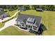 Aerial view of a modern farmhouse with black roof, landscaped front yard and long driveway at 2408 Eddie Howard Rd, Willow Springs, NC 27592