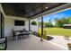 Covered patio features black ceiling, TV, dining table, and lush landscaping with sprawling green backyard at 2408 Eddie Howard Rd, Willow Springs, NC 27592
