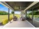 Covered patio includes ceiling fan, wicker seating, lush plants and open view of the green backyard at 2408 Eddie Howard Rd, Willow Springs, NC 27592