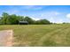 Large parcel of grass with a black metal barn and mature trees on the property at 2408 Eddie Howard Rd, Willow Springs, NC 27592